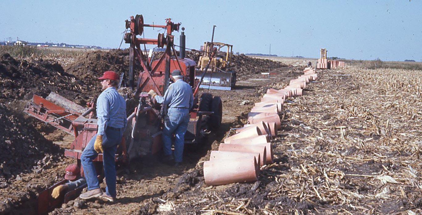 vintage machinery placing pipe in field