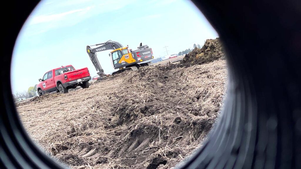 Truck and excavator in field installing pipe